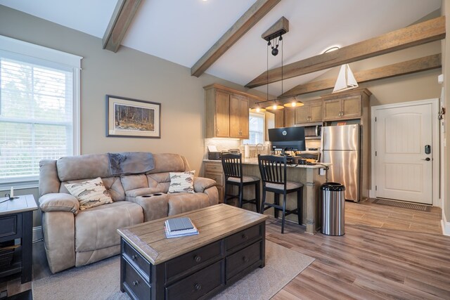 living room with vaulted ceiling with beams and light hardwood / wood-style floors