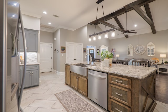 kitchen with a kitchen island with sink, sink, ceiling fan, appliances with stainless steel finishes, and decorative light fixtures