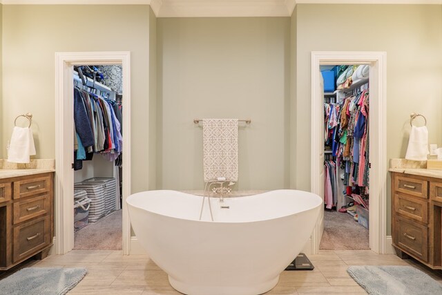 bathroom featuring tile patterned floors, a tub, vanity, and ornamental molding