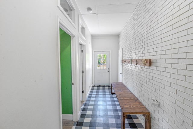 hallway with baseboards, tile patterned floors, and brick wall