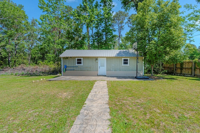 view of front of property with fence, a patio, metal roof, and a front yard