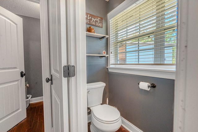 bathroom featuring baseboards, a textured ceiling, wood finished floors, and toilet