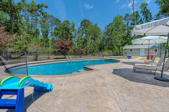 view of pool featuring fence, a fenced in pool, an outbuilding, and a patio area