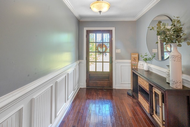 entryway with crown molding, a wainscoted wall, a decorative wall, and dark wood-style flooring