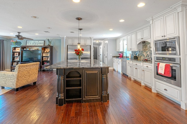 kitchen featuring dark wood-style flooring, built in appliances, dark stone counters, a ceiling fan, and backsplash