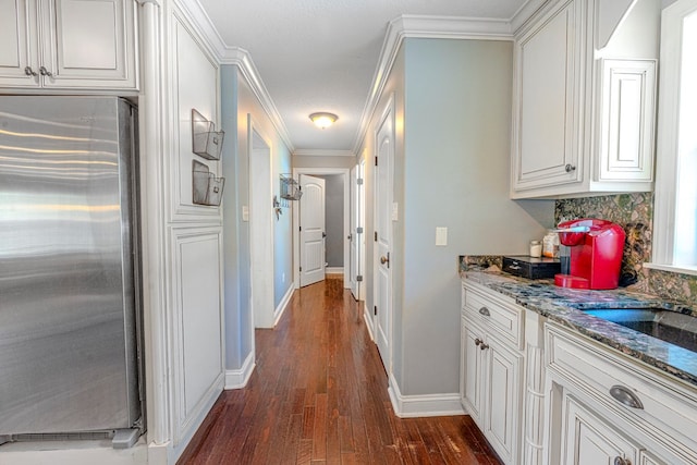 hallway with dark wood-type flooring, baseboards, and crown molding