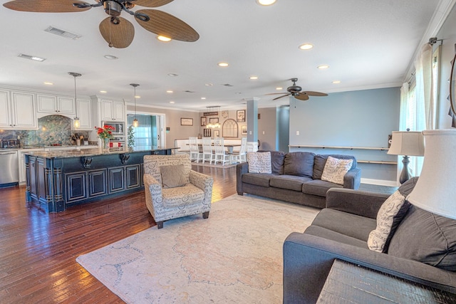 living room with crown molding, a ceiling fan, dark wood finished floors, and visible vents