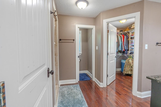 corridor with baseboards, a textured ceiling, and dark wood finished floors