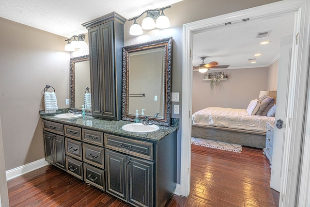 ensuite bathroom with visible vents, a sink, wood-type flooring, and ensuite bath