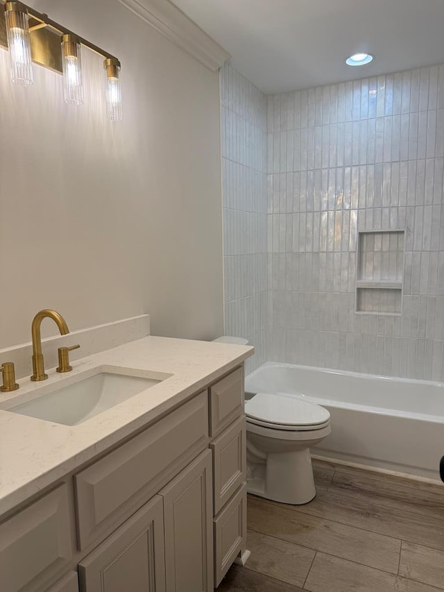 full bathroom with tiled shower / bath combo, vanity, wood-type flooring, and toilet