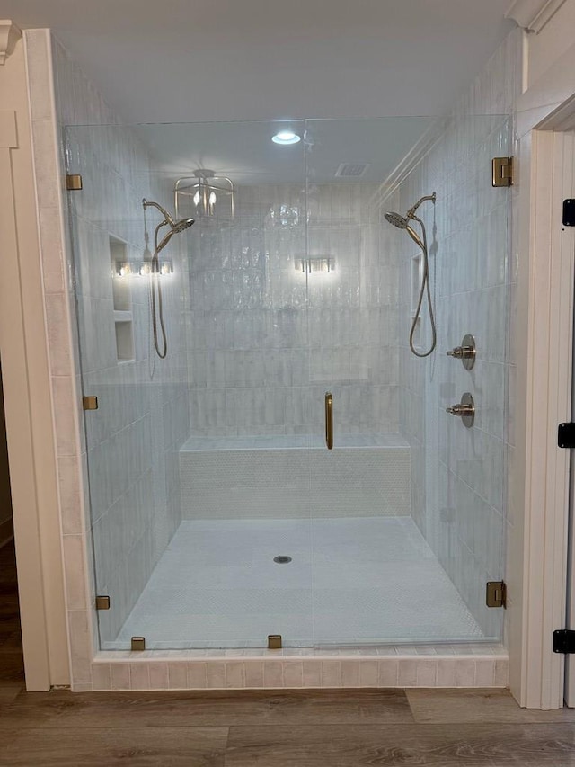 bathroom with wood-type flooring and a shower with shower door