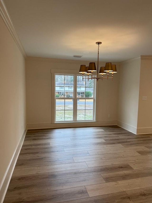 spare room with crown molding, wood-type flooring, and a notable chandelier