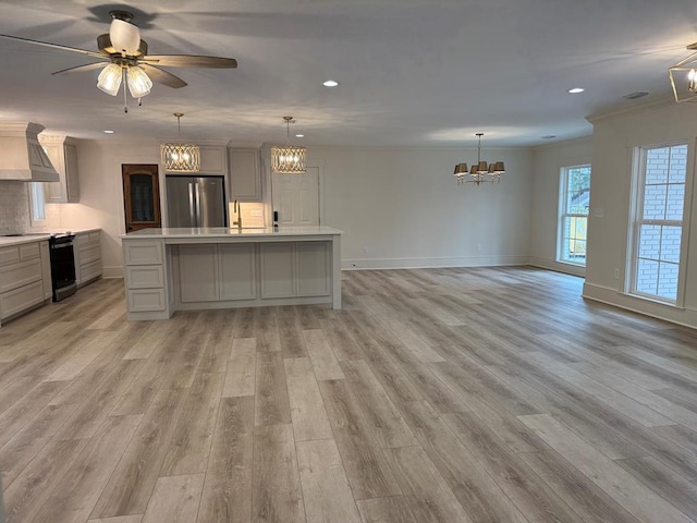 kitchen featuring stainless steel refrigerator, gray cabinetry, custom exhaust hood, hanging light fixtures, and a spacious island