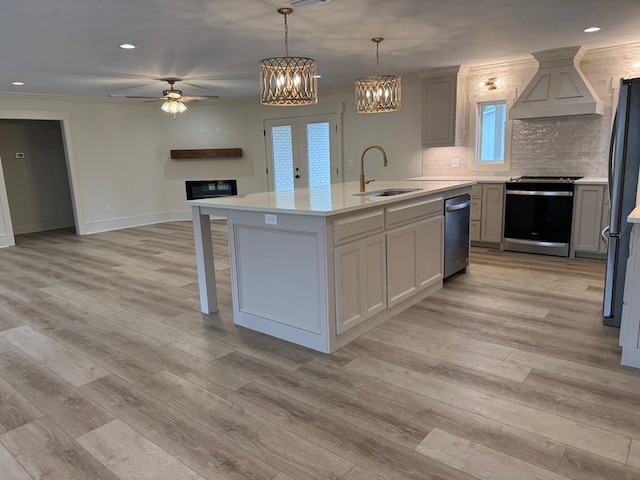 kitchen featuring sink, hanging light fixtures, a center island with sink, custom range hood, and stainless steel appliances