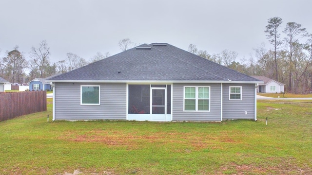 rear view of property with a lawn, roof with shingles, and fence