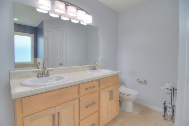 bathroom with a sink, toilet, double vanity, and tile patterned flooring