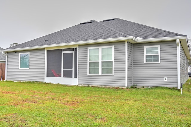 rear view of house featuring a yard and a shingled roof