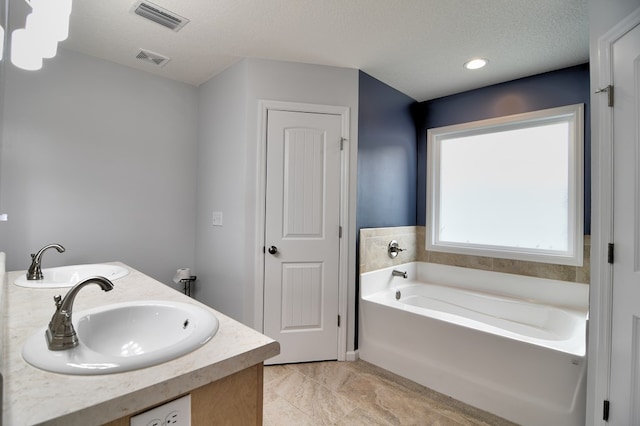 bathroom featuring a sink, visible vents, a textured ceiling, and a bath