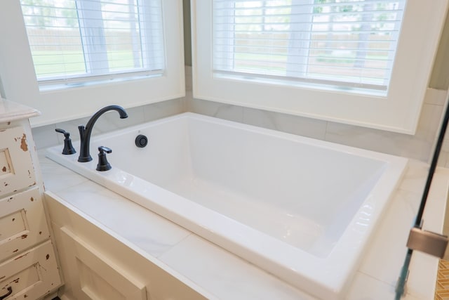 bathroom featuring a healthy amount of sunlight and a relaxing tiled tub