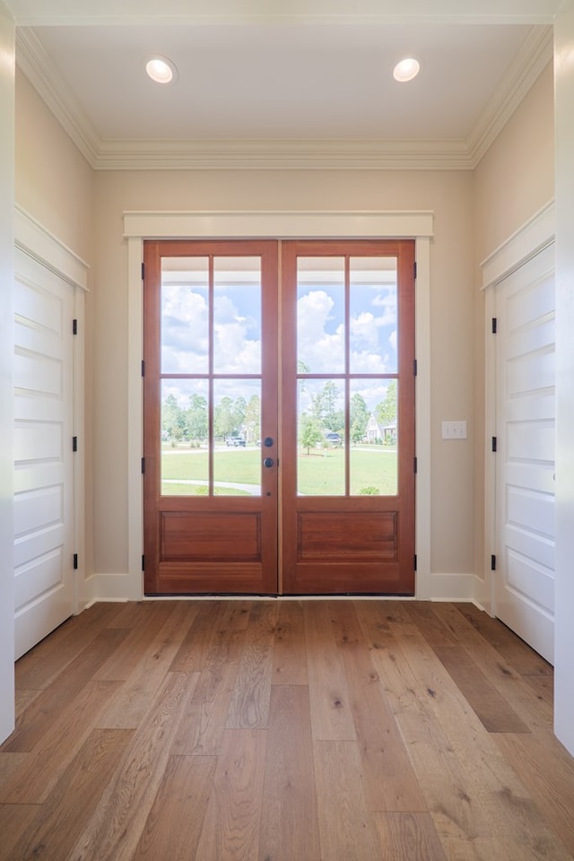 doorway with crown molding and light hardwood / wood-style flooring