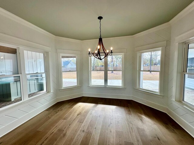 unfurnished dining area with a notable chandelier, crown molding, and wood-type flooring