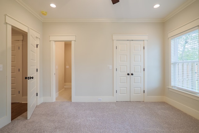 unfurnished bedroom featuring light carpet, crown molding, and a closet