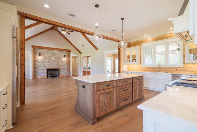 kitchen featuring sink, light hardwood / wood-style floors, white cabinets, a kitchen island, and decorative light fixtures