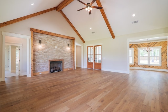 unfurnished living room featuring beamed ceiling, a brick fireplace, high vaulted ceiling, and light hardwood / wood-style flooring