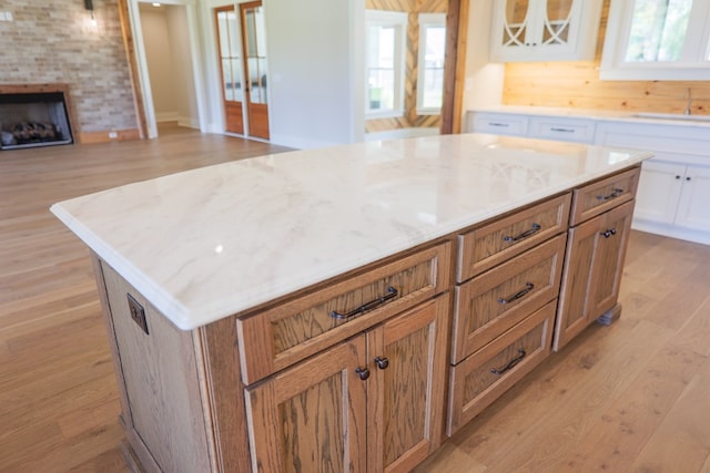 kitchen with sink, white cabinetry, light hardwood / wood-style flooring, a kitchen island, and a fireplace