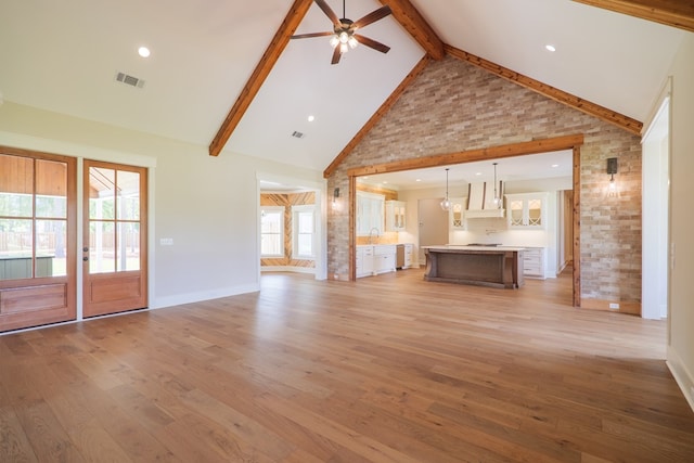 unfurnished living room with sink, high vaulted ceiling, light hardwood / wood-style flooring, ceiling fan, and beam ceiling