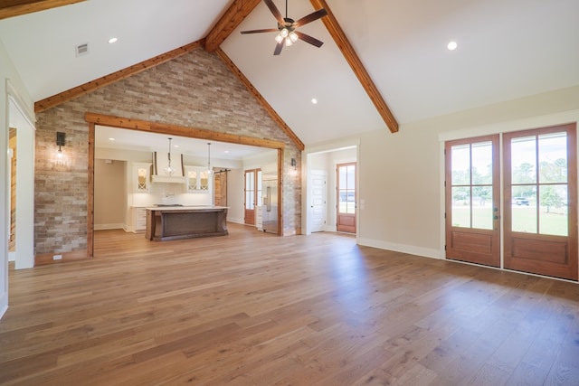 unfurnished living room with beam ceiling, a wealth of natural light, and light hardwood / wood-style floors