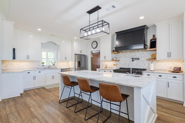 4310 Old Quitman Hwy, Valdosta, GA 31601 - kitchen with stainless steel appliances, custom range hood, tasteful backsplash, white cabinetry, and a center island with sink