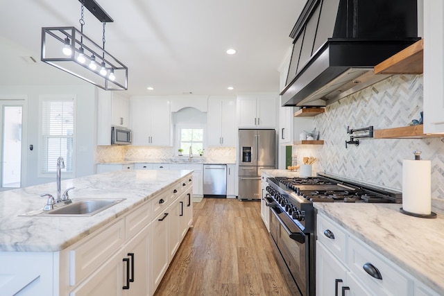 4310 Old Quitman Hwy, Valdosta, GA 31601 - kitchen with appliances with stainless steel finishes, wall chimney exhaust hood, a sink, light wood-type flooring, and backsplash
