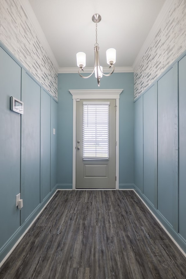 entryway featuring dark wood-type flooring, an inviting chandelier, and crown molding