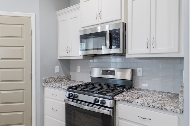 kitchen with light stone counters, stainless steel appliances, decorative backsplash, and white cabinetry