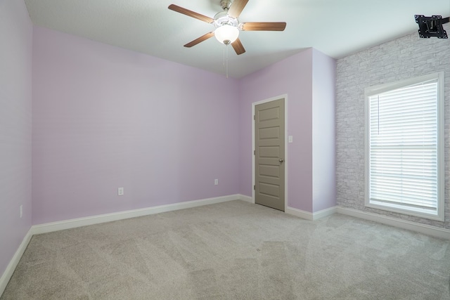 spare room featuring baseboards, light colored carpet, and a ceiling fan