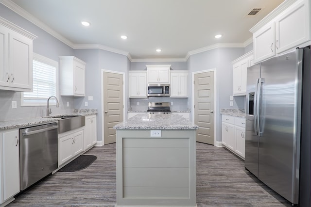 kitchen with a kitchen island, dark wood finished floors, appliances with stainless steel finishes, white cabinets, and a sink