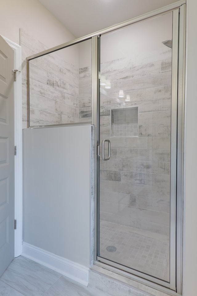 bathroom with baseboards and a stall shower