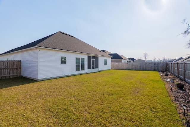 rear view of house with a yard and a fenced backyard