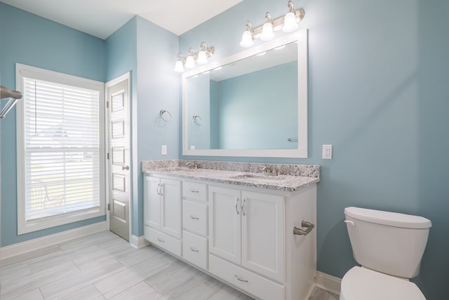 full bath featuring double vanity, toilet, baseboards, and a sink