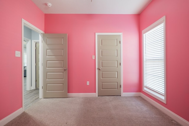 unfurnished bedroom with multiple windows, baseboards, and carpet