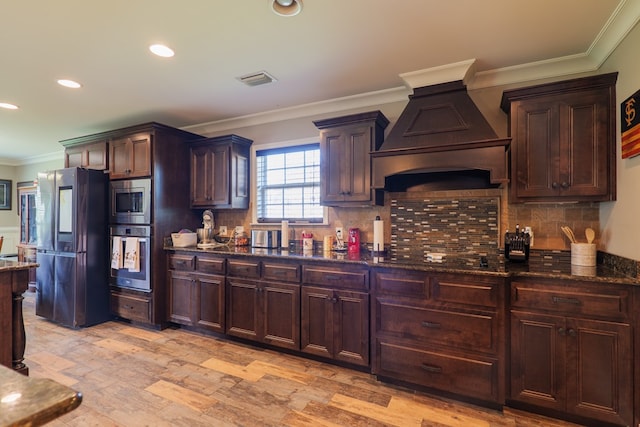 kitchen featuring dark stone counters, black appliances, light hardwood / wood-style flooring, dark brown cabinets, and custom range hood