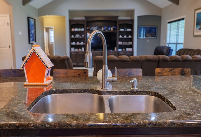 kitchen featuring dark stone countertops, sink, and vaulted ceiling