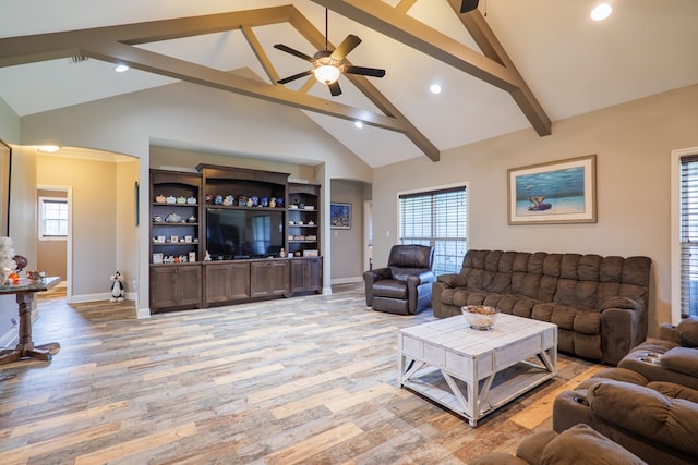 living room with ceiling fan, plenty of natural light, beamed ceiling, and light hardwood / wood-style flooring