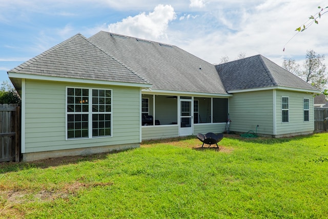 rear view of property featuring a sunroom and a lawn