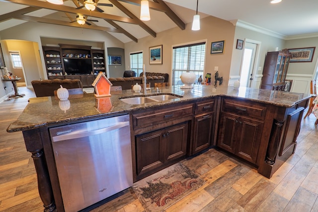 kitchen with a kitchen island with sink, sink, stainless steel dishwasher, dark stone countertops, and decorative light fixtures