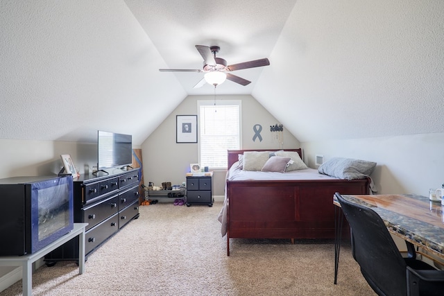 bedroom with lofted ceiling, ceiling fan, light colored carpet, and a textured ceiling