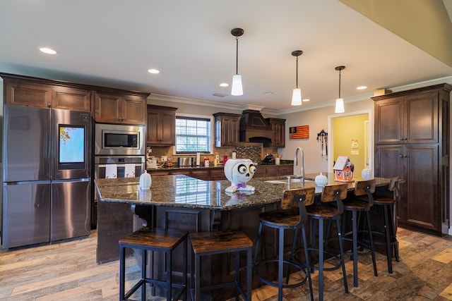 kitchen with backsplash, stainless steel appliances, sink, a large island with sink, and hanging light fixtures