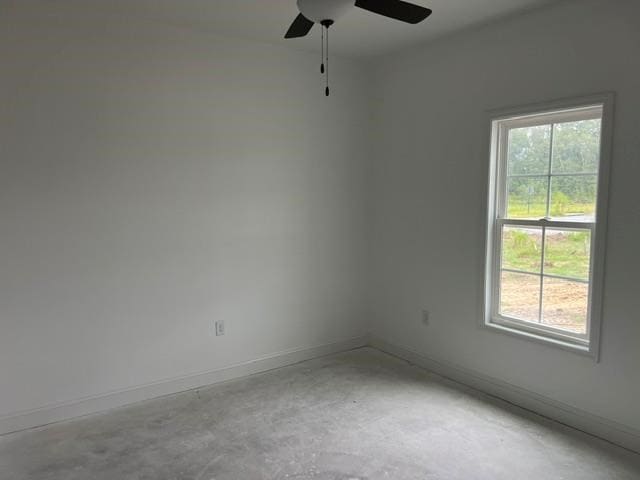 spare room with concrete floors, a ceiling fan, and baseboards