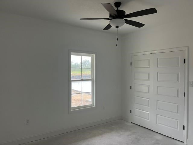 empty room featuring a ceiling fan, concrete floors, and baseboards